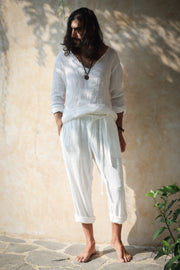 A model wearing the Kian Linen Shirt and matching drawstring pants in a crisp white tone, embodying effortless bohemian elegance. This lightweight, breathable outfit is made from natural fabrics, perfect for slow fashion enthusiasts. From Bird of Paradise, Bali boho clothing